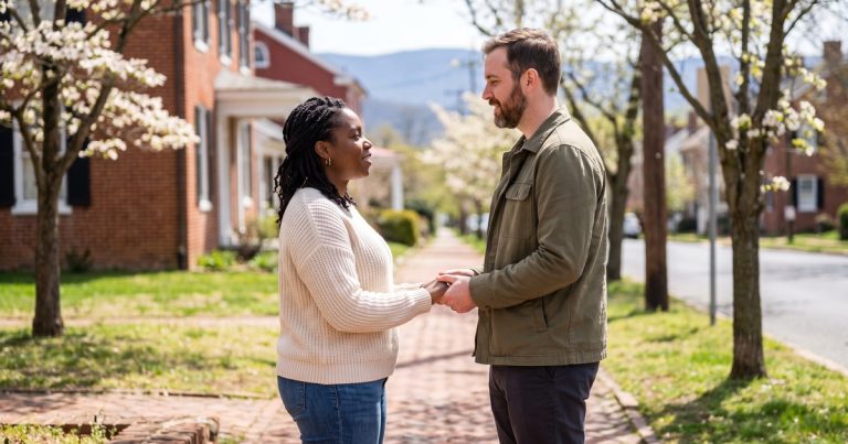 A couple holds hands on a blossom-lined sidewalk in spring, weighing ketamine therapy against talk therapy in Winchester, VA.